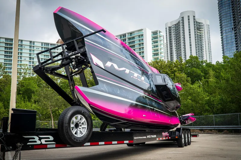 Slide: The Image of 2023 MTI 390XR powerboat on trailer, vibrant pink and black design, urban skyline backdrop. - 12