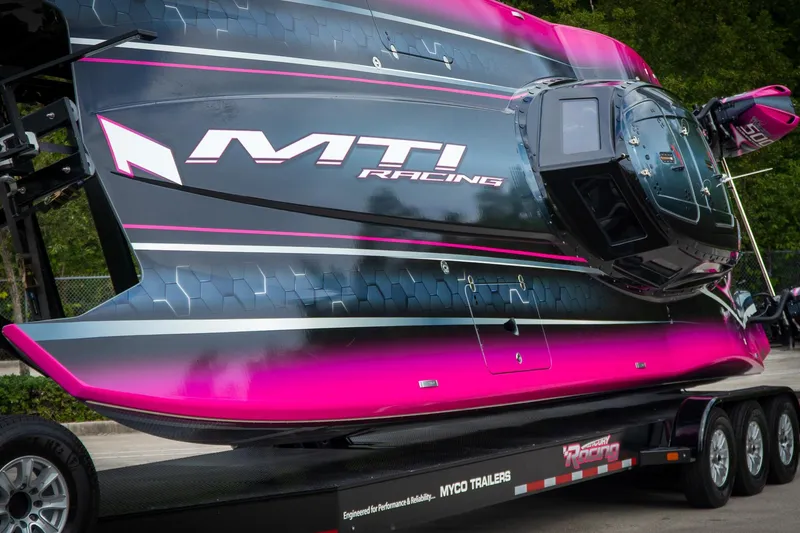 Slide: The Image of 2023 MTI 390XR racing boat with vibrant pink and black design on trailer. - 25