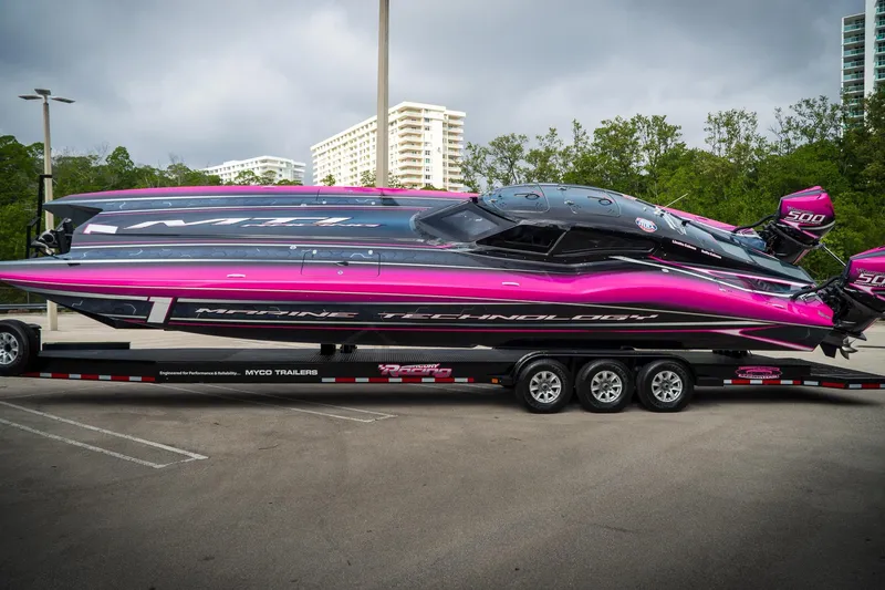 Slide: The Image of 2023 MTI 390XR powerboat with vibrant pink and black design on a trailer. - 26