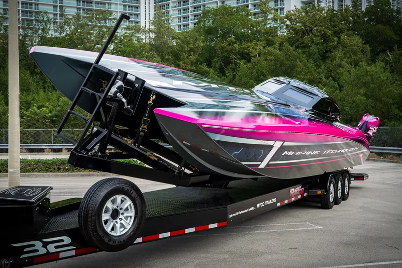 Slide: The Image of 2023 MTI 390XR powerboat on trailer, vibrant pink and gray design, parked outdoors. - 3