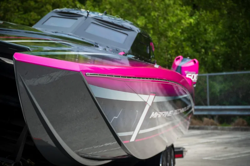 Slide: The Image of 2023 MTI 390XR powerboat with vibrant pink and gray design, parked outdoors. - 30