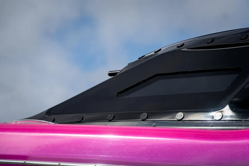 Slide: The Image of Close-up of 2023 MTI 390XR boat with sleek black and pink design. - 33