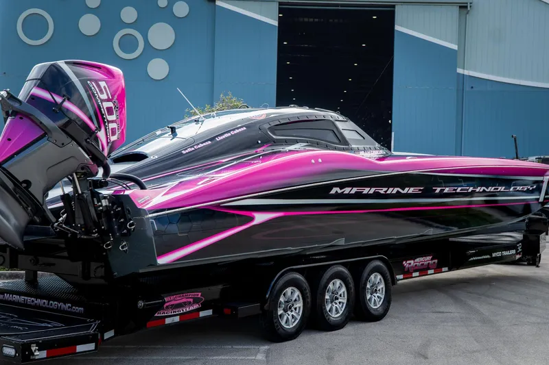 Slide: The Image of 2023 MTI 390XR powerboat with vibrant pink and black design, parked on a trailer. - 37