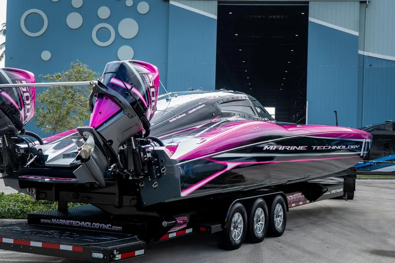 Slide: The Image of 2023 MTI 390XR powerboat with vibrant pink and black design on a trailer. - 38