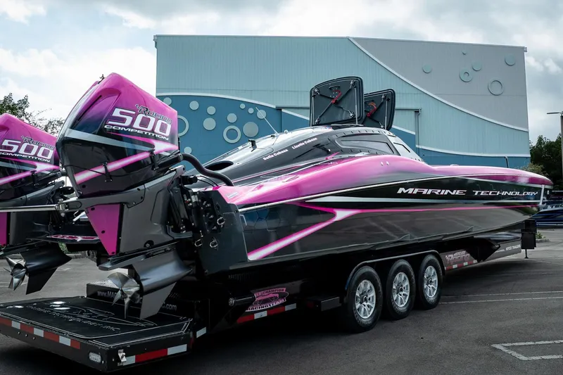 Slide: The Image of 2023 MTI 390XR powerboat with vibrant pink and black design on a trailer. - 52