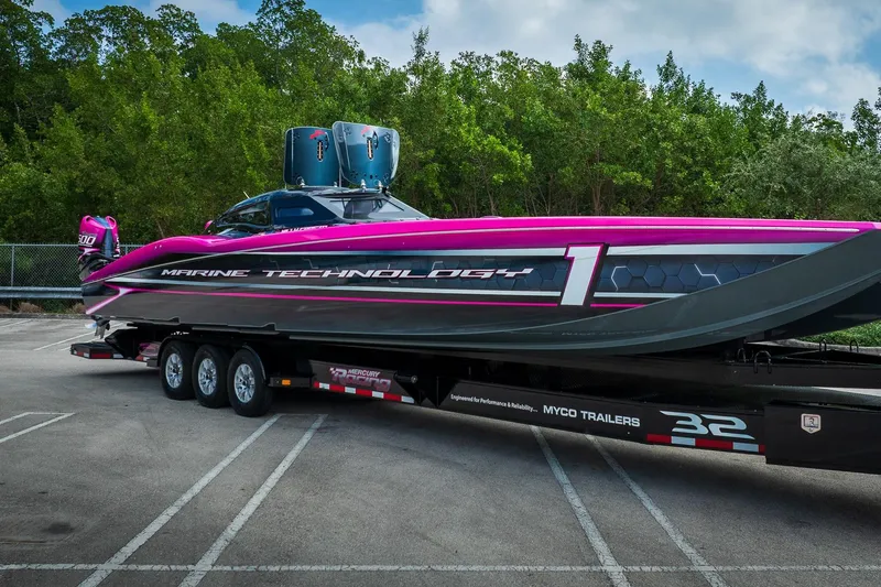 Slide: The Image of 2023 MTI 390XR powerboat on trailer, vibrant pink and black design, parked outdoors. - 56
