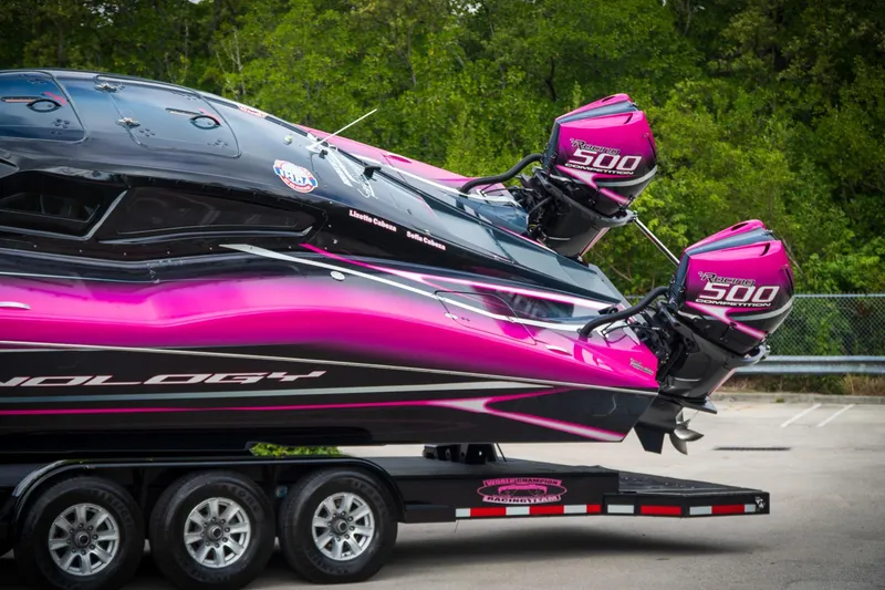Slide: The Image of 2023 MTI 390XR boat with vibrant pink and black design on a trailer. - 6