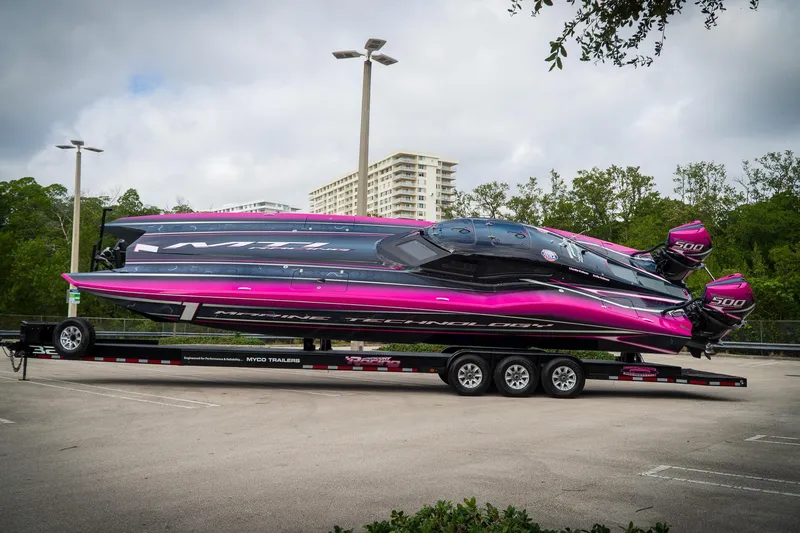 Slide: The Image of 2023 MTI 390XR powerboat with vibrant pink and black design on a trailer. - 9