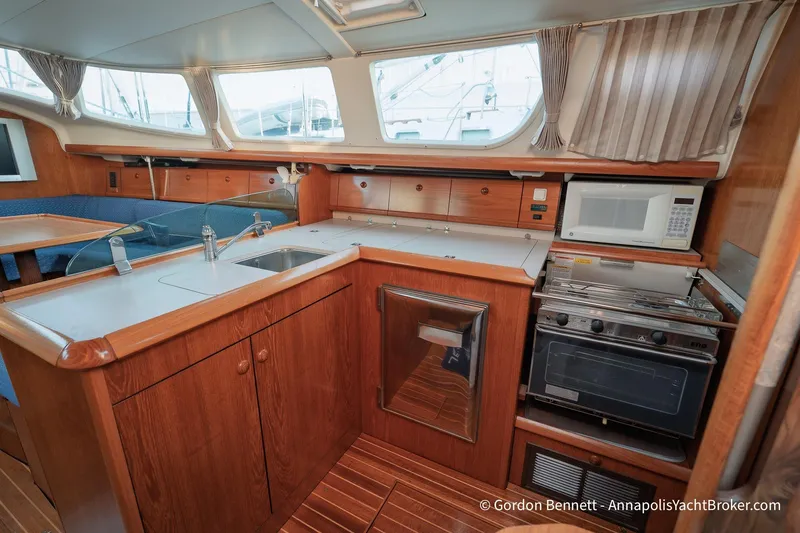 Slide: The Image of 2004 Jeanneau Sun Odyssey 43 DS yacht interior kitchen with wood cabinetry and modern appliances. - 34