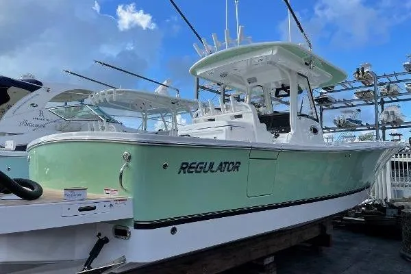 Slide: The Image of 2021 Regulator 34 boat with mint green hull, docked under a cloudy sky. - 24