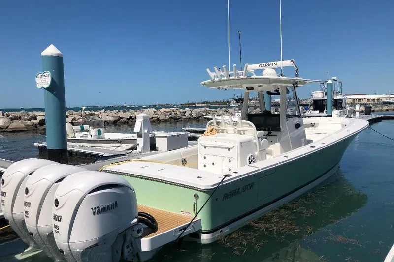 Slide: The Image of 2021 Regulator 34 boat docked with triple Yamaha engines, clear blue sky. - 4