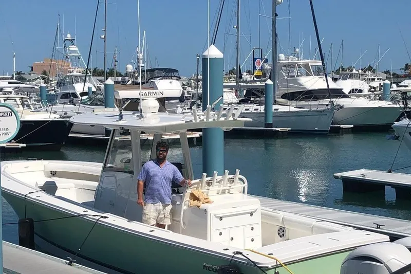 Slide: The Image of Man on a 2021 Regulator 34 boat docked at a marina with other boats. - 6