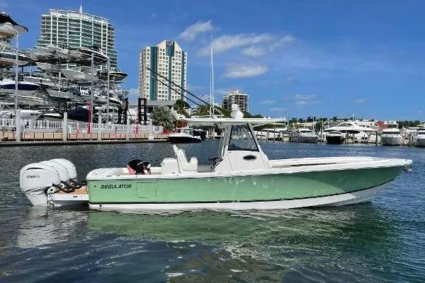 Slide: The Image of 2021 Regulator 34 boat docked in marina, clear sky, modern buildings in background. - 7