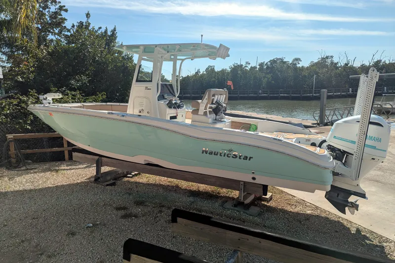 Slide: The Image of 2020 NauticStar 251 Hybrid boat on display, surrounded by palm trees and residential buildings. - 2