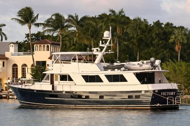 The Image of Classic 1988 Burger Motoryacht docked near palm trees and luxury homes. - 2