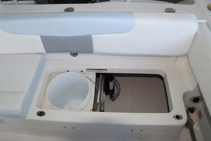 Slide: The Image of 2026 Robalo R202 Explorer boat storage compartment with bucket and pump. - 14