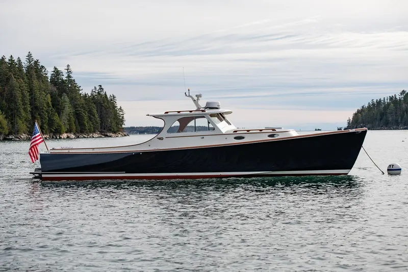 Slide: The Image of 2001 Hinckley Picnic Boat Classic on calm water, surrounded by trees. - 10