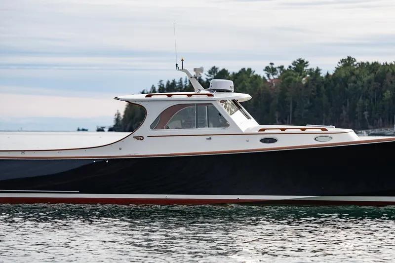 Slide: The Image of 2001 Hinckley Picnic Boat Classic on calm water with forested shoreline background. - 11