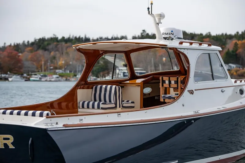 Slide: The Image of 2001 Hinckley Picnic Boat Classic with striped seating, docked by a scenic shoreline. - 17