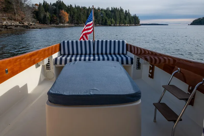Slide: The Image of 2001 Hinckley Picnic Boat Classic with striped seating, American flag, scenic coastal backdrop. - 32