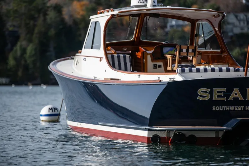 Slide: The Image of 2001 Hinckley Picnic Boat Classic on serene water, featuring elegant design and striped seating. - 52