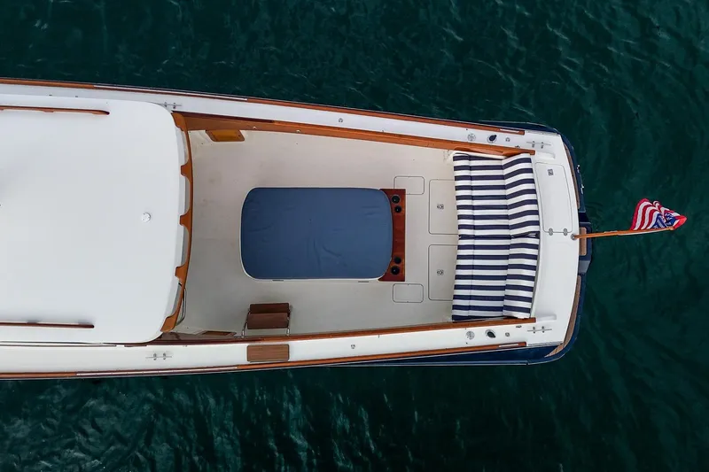 Slide: The Image of Aerial view of 2001 Hinckley Picnic Boat Classic on water, featuring striped seating and American flag. - 9