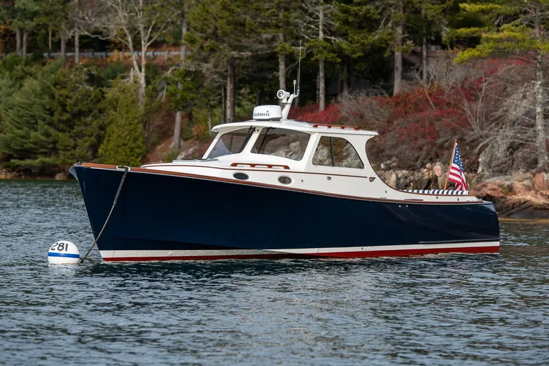 The Image of 2001 Hinckley Picnic Boat Classic moored on a serene lake with forested background. - 0