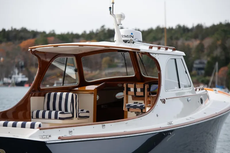 Slide: The Image of 2001 Hinckley Picnic Boat Classic with striped seating, docked on a serene lake. - 18