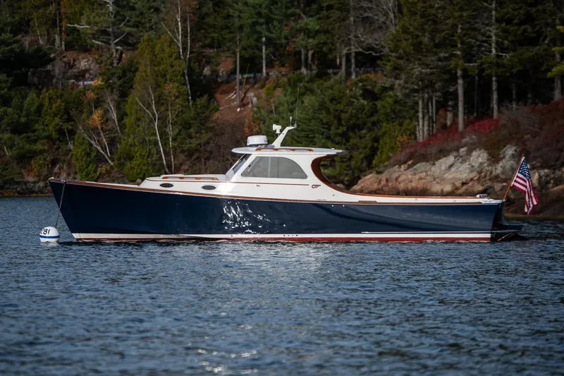 Slide: The Image of 2001 Hinckley Picnic Boat Classic on serene water, surrounded by lush greenery. - 2