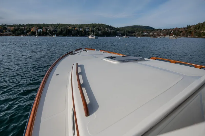 Slide: The Image of 2001 Hinckley Picnic Boat Classic cruising on a serene lake with forested shoreline. - 23