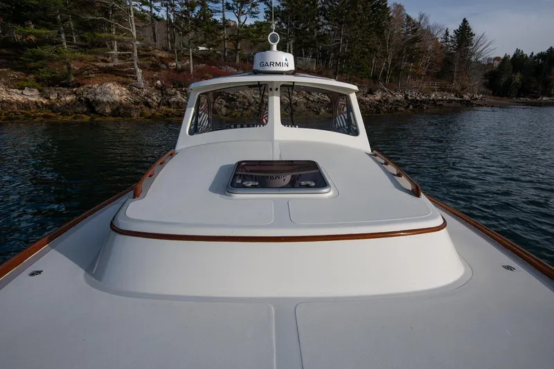 Slide: The Image of 2001 Hinckley Picnic Boat Classic on calm water near rocky shoreline. - 27