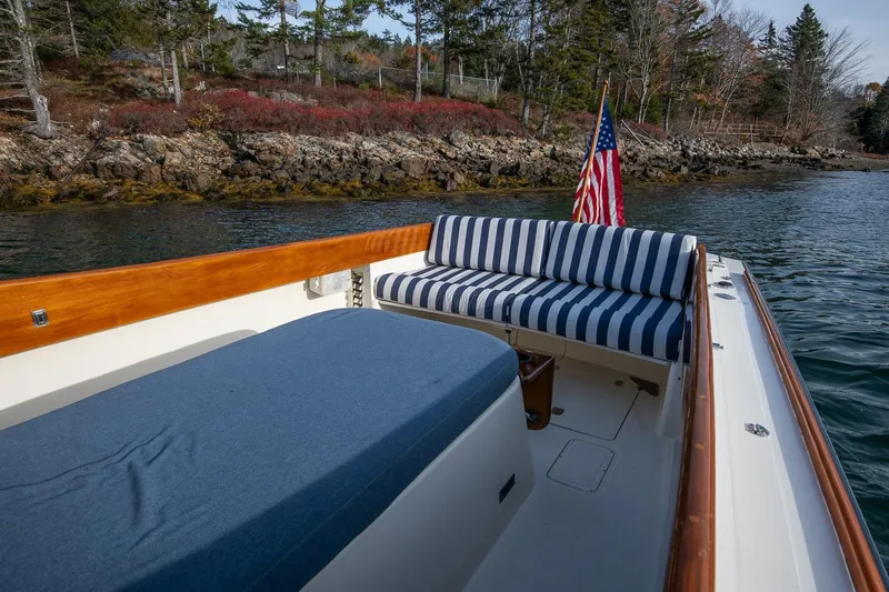 Slide: The Image of 2001 Hinckley Picnic Boat Classic with striped seating, American flag, and scenic shoreline view. - 30