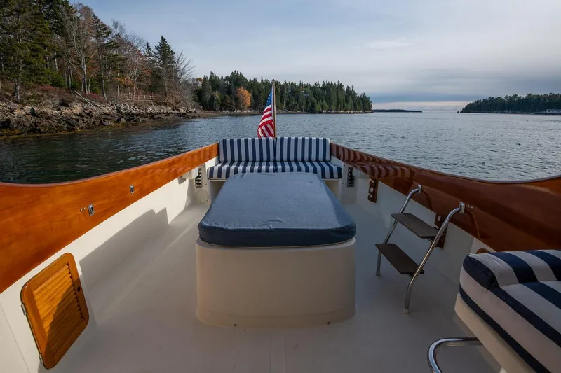 Slide: The Image of 2001 Hinckley Picnic Boat Classic with striped seating, cruising on a serene lake. - 31