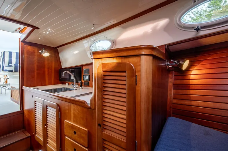 Slide: The Image of Interior of 2001 Hinckley Picnic Boat Classic with wooden cabinetry and compact kitchen area. - 41