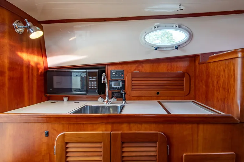 Slide: The Image of 2001 Hinckley Picnic Boat Classic interior with wooden cabinetry, sink, and microwave. - 42