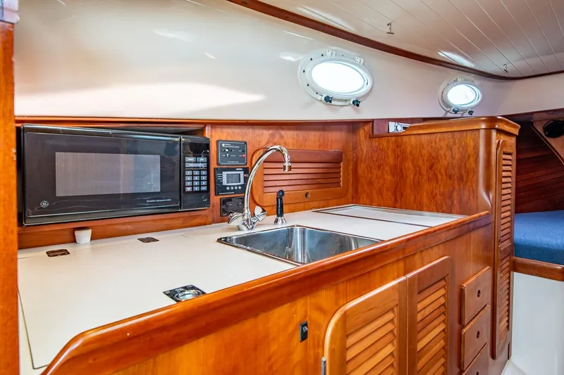 Slide: The Image of Hinckley Picnic Boat Classic 2001 interior with wooden cabinetry, sink, and microwave. - 43