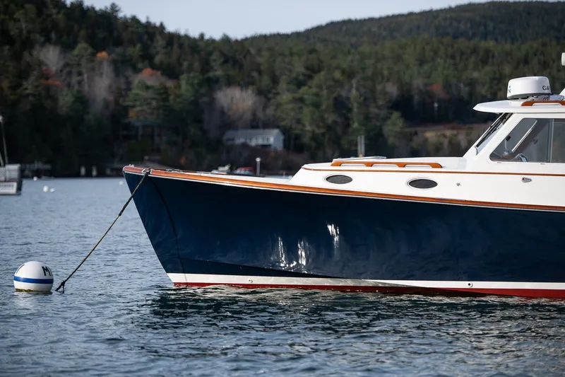 Slide: The Image of 2001 Hinckley Picnic Boat Classic moored on calm water with forested background. - 49