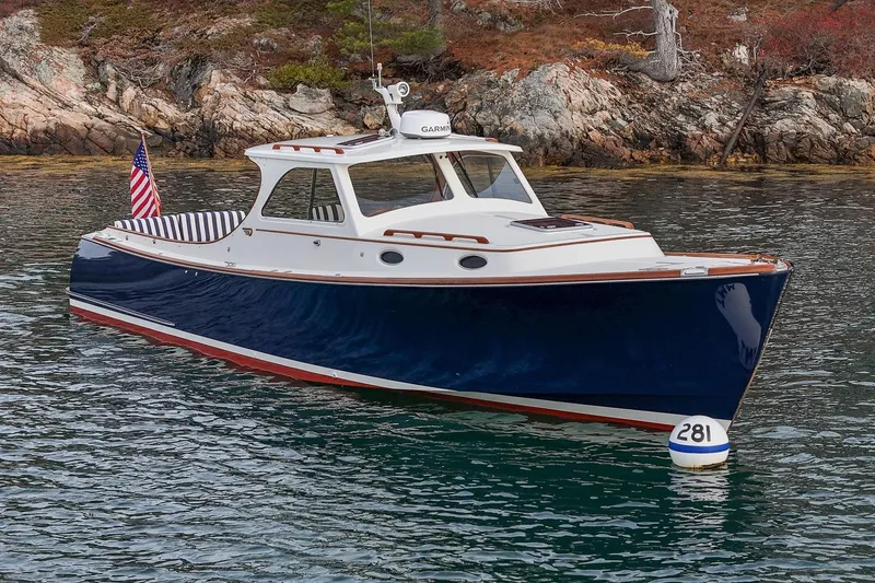 Slide: The Image of 2001 Hinckley Picnic Boat Classic on water, near rocky shoreline. - 5
