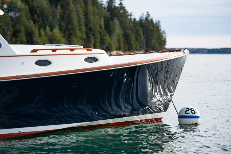 Slide: The Image of 2001 Hinckley Picnic Boat Classic on water near forested shoreline. - 51