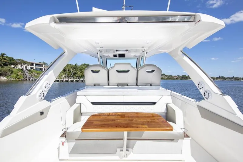 Slide: The Image of Manufacturer Provided Image: 2025 Tiara Yachts 34 LS boat interior with seating and wooden table, under clear blue sky. - 46
