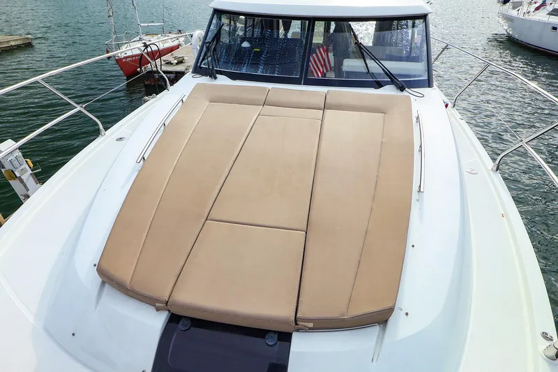 Slide: The Image of 2015 Jeanneau NC 14 yacht with spacious sunbathing deck, docked at marina. - 2