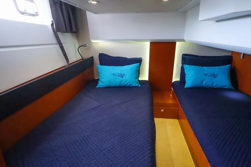 Slide: The Image of 2015 Jeanneau NC 14 cabin with twin beds, blue bedding, and teal pillows. - 21