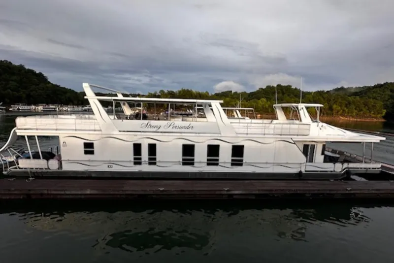 The Image of 2007 Sharpe 18 x 90 houseboat docked on a serene lake with lush greenery. - 1