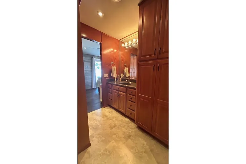 Slide: The Image of Luxurious bathroom with wooden cabinets, granite countertop, and warm lighting in a 2007 Sharpe model. - 19