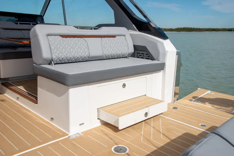 Slide: The Image of 2026 Regal LX43 boat interior with gray seating and wooden deck, on a sunny day. - 13