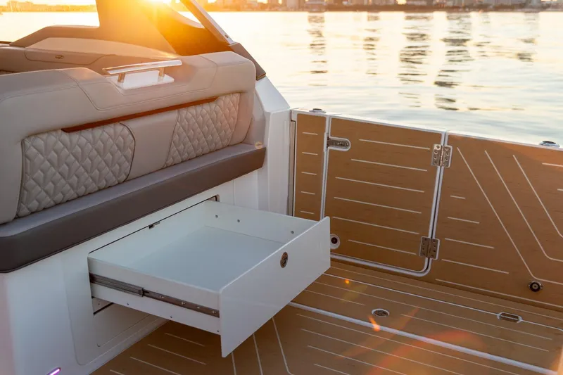 Slide: The Image of 2026 Regal LX43 boat interior with open storage drawer, sunset reflecting on water. - 14