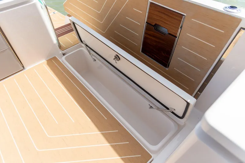 Slide: The Image of 2026 Regal LX43 boat storage compartment with wood finish and open hatch. - 18