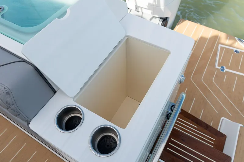 Slide: The Image of Open storage compartment on 2026 Regal LX43 boat with cup holders and wooden deck. - 25