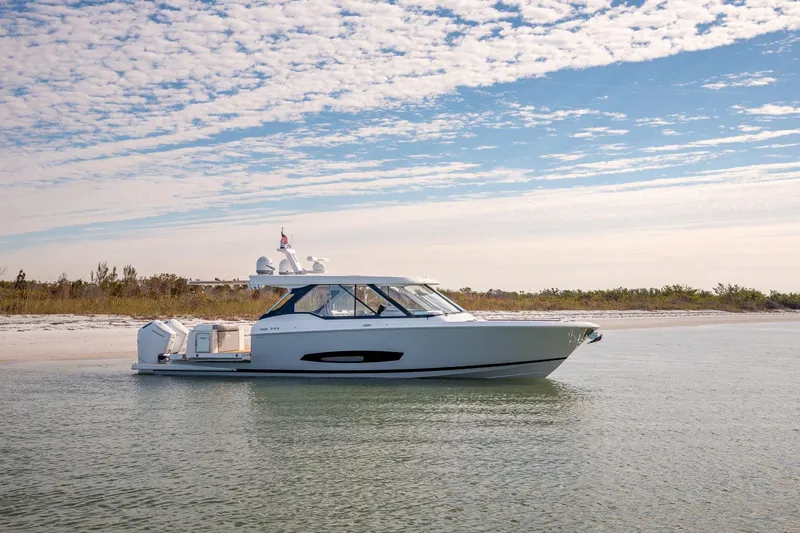 Slide: The Image of 2026 Regal LX43 boat on calm water near a sandy beach under a partly cloudy sky. - 6