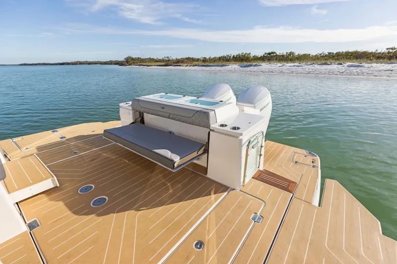 Slide: The Image of 2026 Regal LX43 boat with spacious deck and seating, near a serene shoreline. - 7